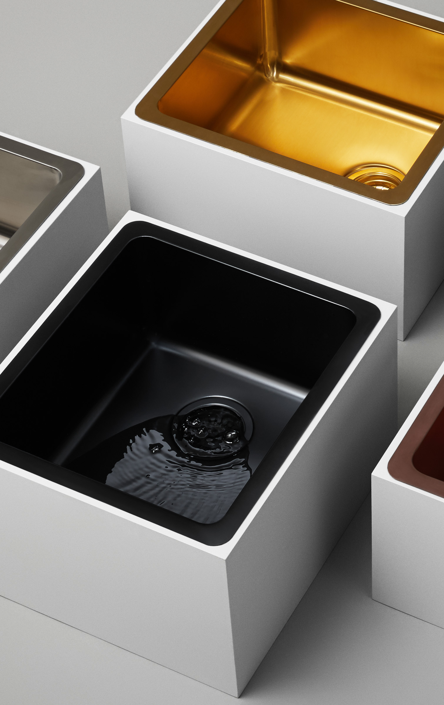 Still life photography showcasing Titan medium bowl sinks in brass and matte black, highlighting the contrast and elegance of brass and black kitchen sinks.