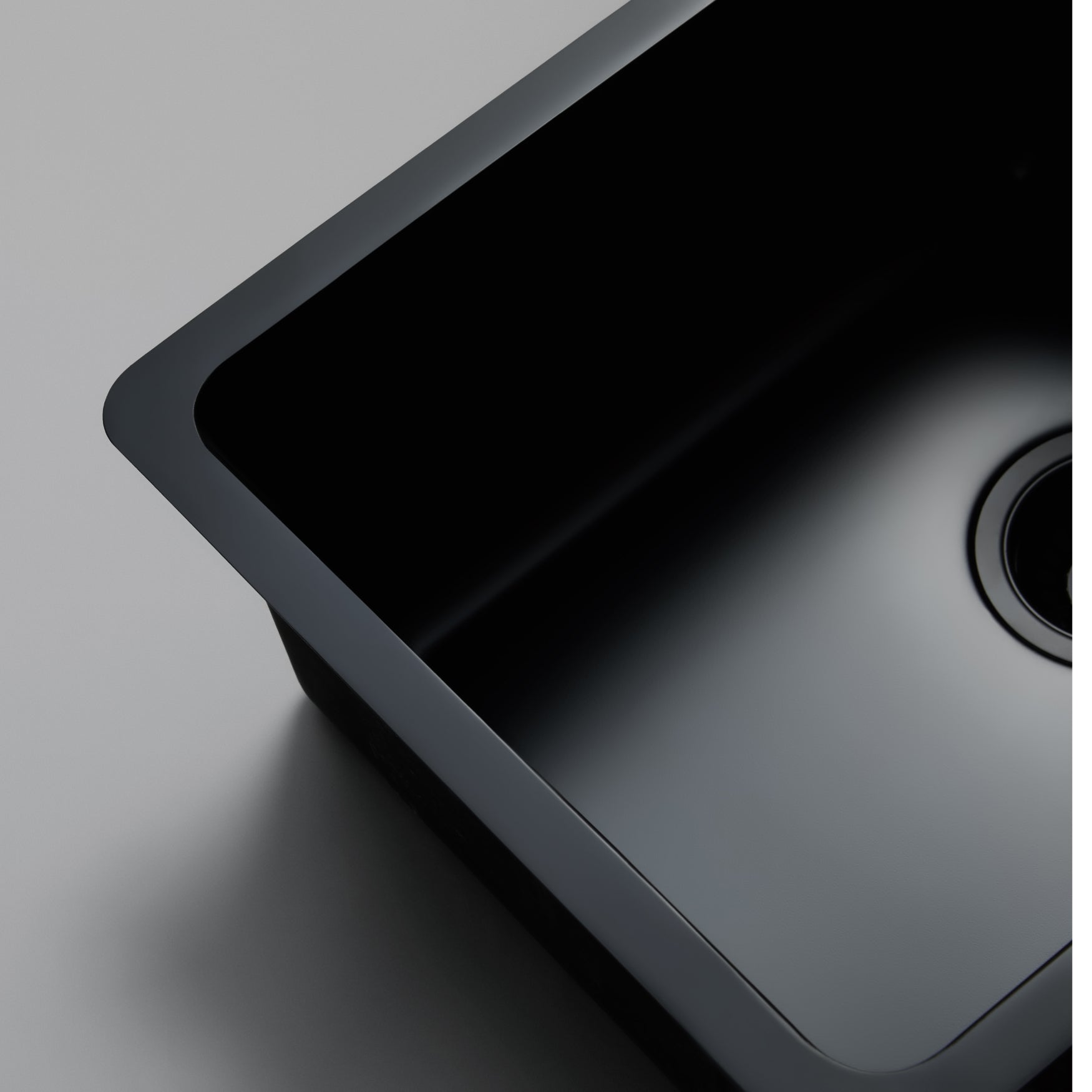 Close-up still life image of a Titan large bowl black kitchen sink against a gray background, highlighting the elegant design of the brass sink.